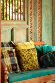 Cushions on wooden bench in front of painted and carved wooden wall
