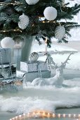 White, china stag ornament on faux-fur rug under Christmas tree with white decorations