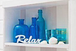 Blue ornamental bottles and glasses on white shelf
