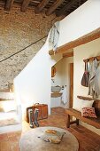 Mit Terrakotta gefliester Vorraum in mediterranem Landhaus mit Natursteinmauer und rustikaler Holzbalkendecke