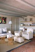 Pale upholstered furniture on castors and wooden stool as side table in Mediterranean living room with ribbed ceiling and terracotta tiles