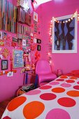 Girl's bedroom with pink walls, colourful items decorating wall and fairy lights