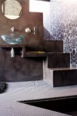 Open-plan wash area with glass counter-top basin next to steps painted with grey polished spatula effect