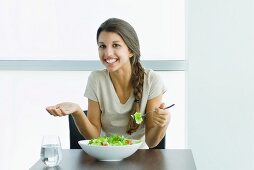 Lächelnde junge Frau isst Salat