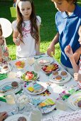 Children around sweets table at outdoor birthday party