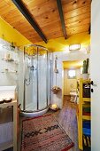 Modern bathroom with wooden ceiling and shower cubicle; African runner on parquet floor