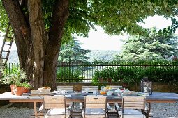 Frühstücken auf einer mediterranen Terrasse und Blick über Bäume in die Landschaft