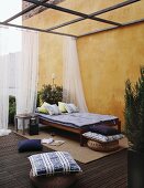 Mediterrane Wohnterrasse mit Bett, Sitzkissen und elegantem Moskitonetz