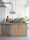 Groceries and condiments on free-standing kitchen island in loft-style interior with woman in background