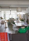 Loft-style interior with several tables and various chairs in front of open-plan kitchen