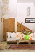 Rustic coffee table in front of sofa with white cushions and fitted cupboards in pale wood