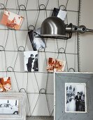 Pinnwand aus Metallgeflecht mit Fotos an Wand und Retro Lampenschirm