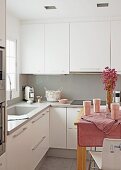 Kitchen with white fitted cupboards and wooden table