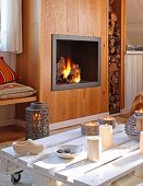 Table made from pallet painted white in front of open fire in rustic living room