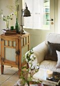 Upholstered couch and retro table lamp on small wooden cabinet in front of back door