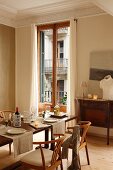 Classic chairs at set table in front of French windows in grand dining room