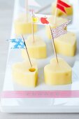 Heart-shaped pieces of cheese with toothpick flags made using masking tape
