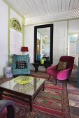 Hotel lounge - glass table and colourful armchairs on patterned rug in white wood-clad lobby