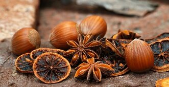 An arrangement of star anise, hazelnuts and dried orange slices