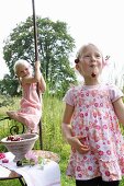 Two little blond girls eating cherries in a garden