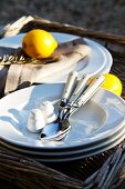 Lemons, plates and cutlery on wicker tray