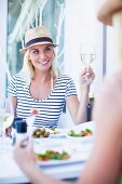 Frau mit Strohhut trinkt Wein im Restaurant
