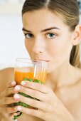 Woman drinking glass of vegetable juice, looking at camera