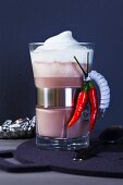 A glass of cocoa with chilli peppers and milk foam