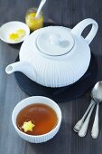 A tea pot, a bowl of tea with a piece of star-shaped lemon zest