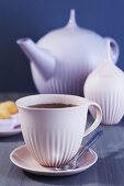 A cup of tea with a tea pot and a sugar pot