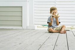 Kind auf Holzboden sitzend mit Seesternen in der Hand