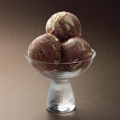 Three balls of chocolate ice cream in a glass bowl