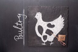 Gezeichnetes Huhn und Etikett mit englischer Bezeichnung auf einer Schiefertafel