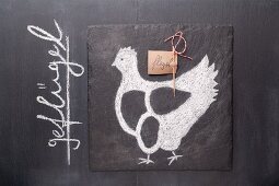 A sketch of a chicken and a written label on a chalkboard