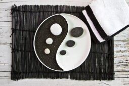 Ying-Yang-Schale mit schwarzem Lavagestein und weissen Kieseln auf Bambus-Set