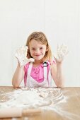 A little girl showing hands covered in dough