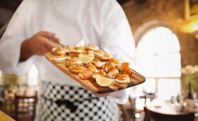 A cook showing a platter of salmon canapes