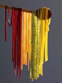 Home-made tagliatelle hanging on a wooden spoon