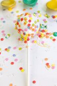 Weisser Cake Pop mit bunten Zuckerstreuseln