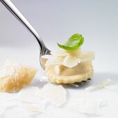 Ravioli mit Parmesanspänen und Basilikumblatt auf Gabel