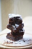 Gestapelte Brownies mit Puderzucker bestreuen