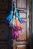 Farbige Kordelquasten an Möbelgriff einer Schranktür in orientalischem Stil