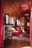 View into old circus caravan with vintage cooker next to sofa in cosy, wood-panelled interior