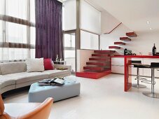 Designer interior furnishings and counter with barstools in open-plan kitchen below stairs leading to gallery