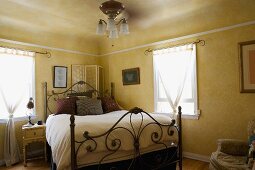 Naturally lit bedroom with decorative iron bed.