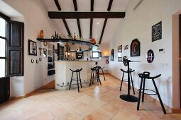 Offener Wohnraum mit Bar und Bistrohockern in mediterranem Landhaus mit Fliesenboden