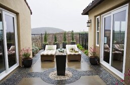 Geschützte Terrasse mit Sonnenliegen zwischen dekorativen Kieselpflasterstreifen
