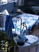 Metal bed with a bedspread decorated with a blue and white pattern