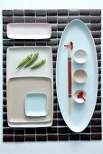 A place mat and a Japanese place setting with assorted dishes arranged geometrically