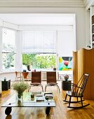 Glass coffee table on castors and designer chairs in living room